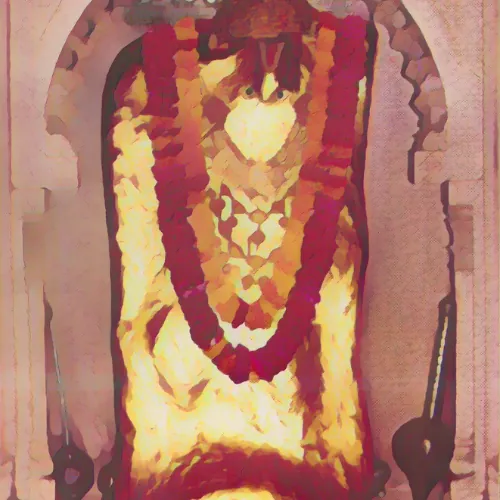 लाल फूलों की माला से सुसज्जित एक पत्थर की मूर्ति एक धनुषाकार कक्ष के अंदर खड़ी है, जो गर्म रोशनी से प्रकाशित है और बनावट वाली पृष्ठभूमि से घिरी हुई है, जो महेंदीपुर बालाजी की कहानी के रहस्य को उजागर करती है।.